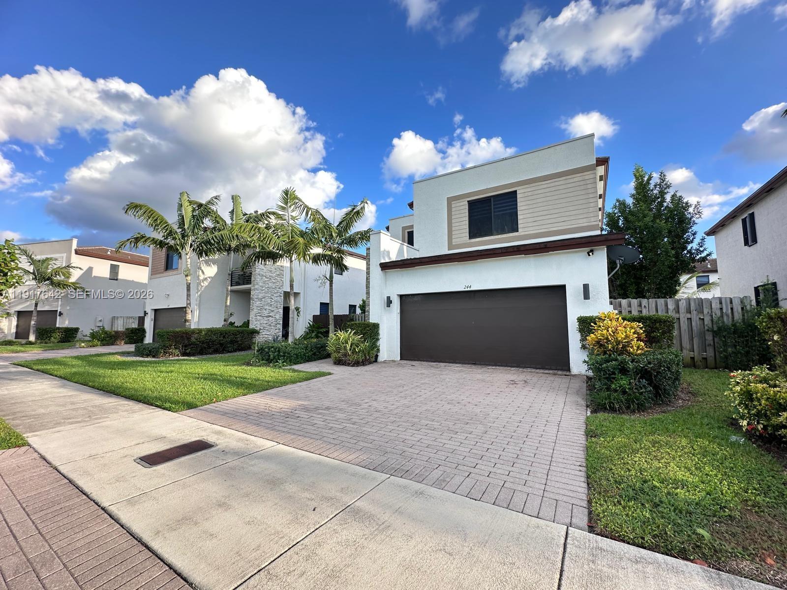 244 Northeast 210th Way, Unit 244 Miami, FL 33179 - Photo 2 of 32 a front view of a house with a garden and yard