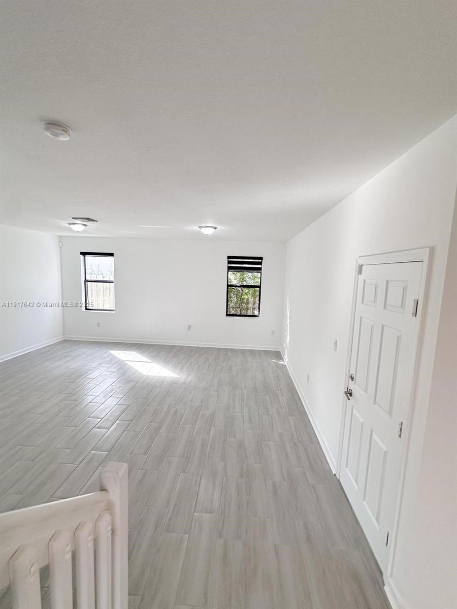 244 Northeast 210th Way, Unit 244 Miami, FL 33179 - Photo 22 of 32 an empty room with wooden floor and windows