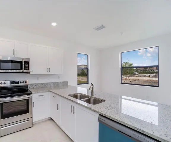 a kitchen with stainless steel appliances a stove microwave and sink