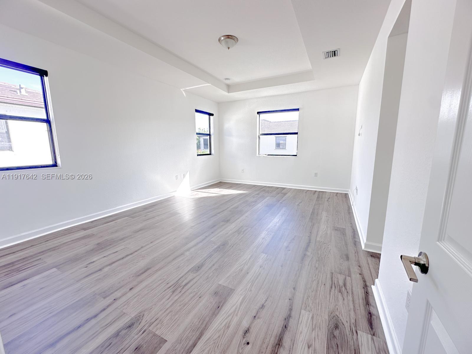 244 Northeast 210th Way, Unit 244 Miami, FL 33179 - Photo 5 of 32 an empty room with wooden floor and windows