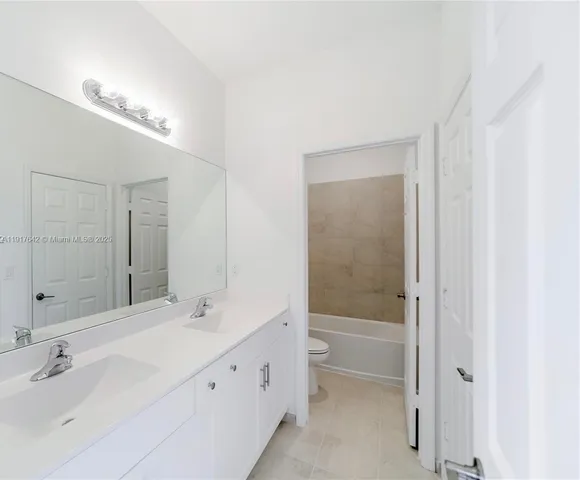 a bathroom with a bathtub shower sink vanity and mirror