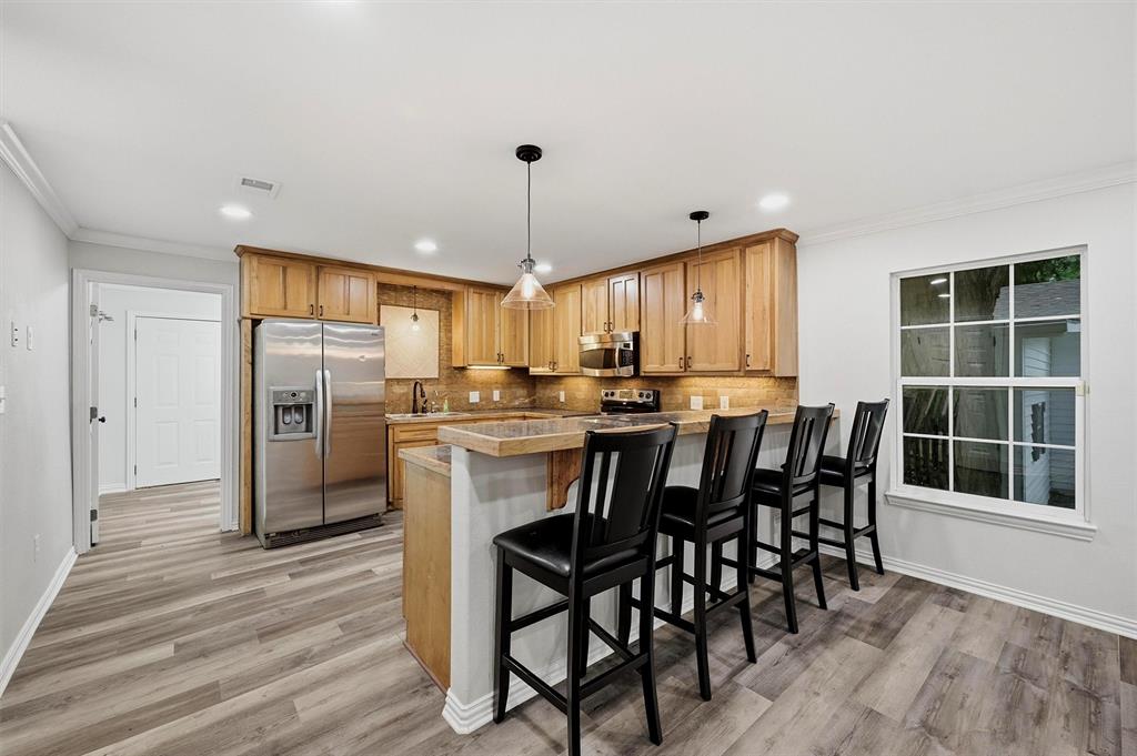 909 Thatcher Street Denison, TX 75020 - Photo 5 of 24 a kitchen with stainless steel appliances kitchen island granite countertop a table chairs and a window