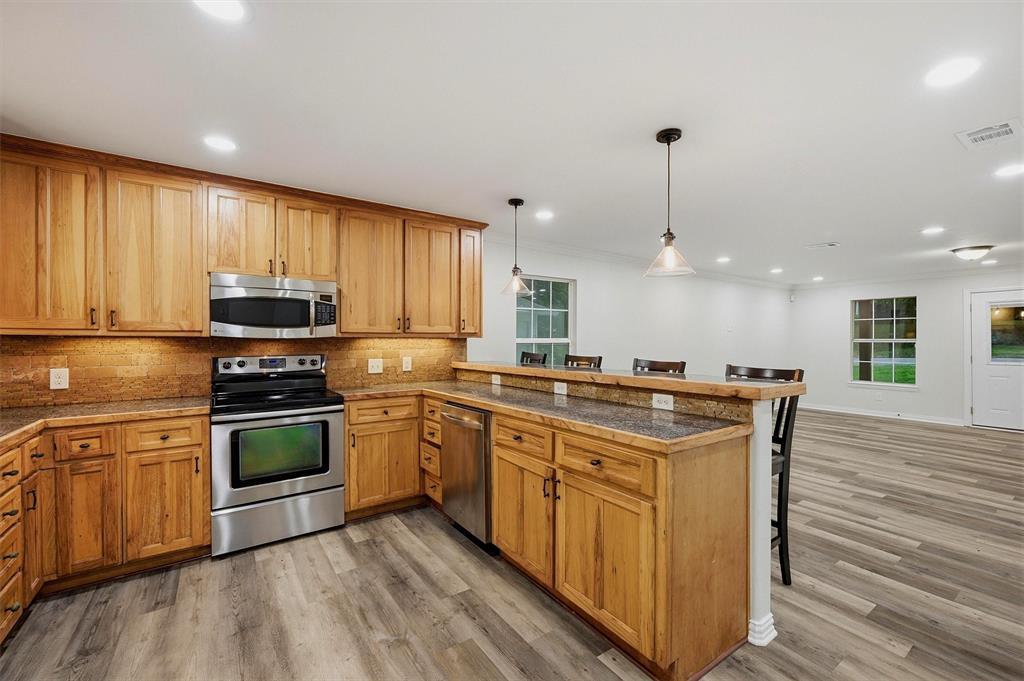 909 Thatcher Street Denison, TX 75020 - Photo 6 of 24 a kitchen with stainless steel appliances granite countertop a stove a sink and a microwave