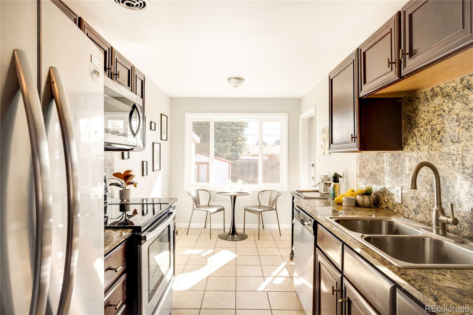 2438 South Perry Street Denver, CO 80219 - Photo 5 of 24 a kitchen with stainless steel appliances a sink a stove and a refrigerator with wooden floor