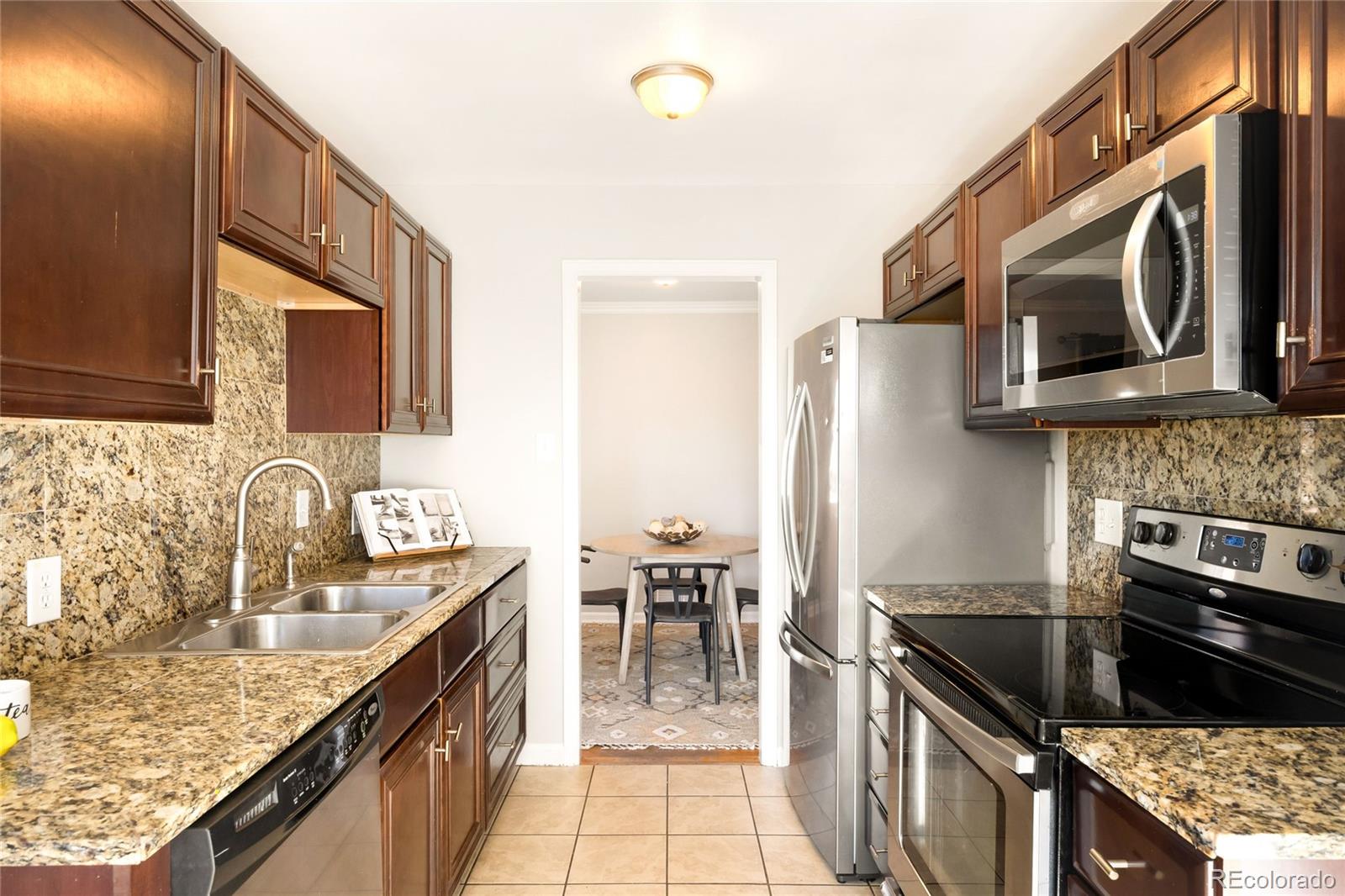2438 South Perry Street Denver, CO 80219 - Photo 6 of 24 a kitchen with stainless steel appliances granite countertop a sink stove and refrigerator
