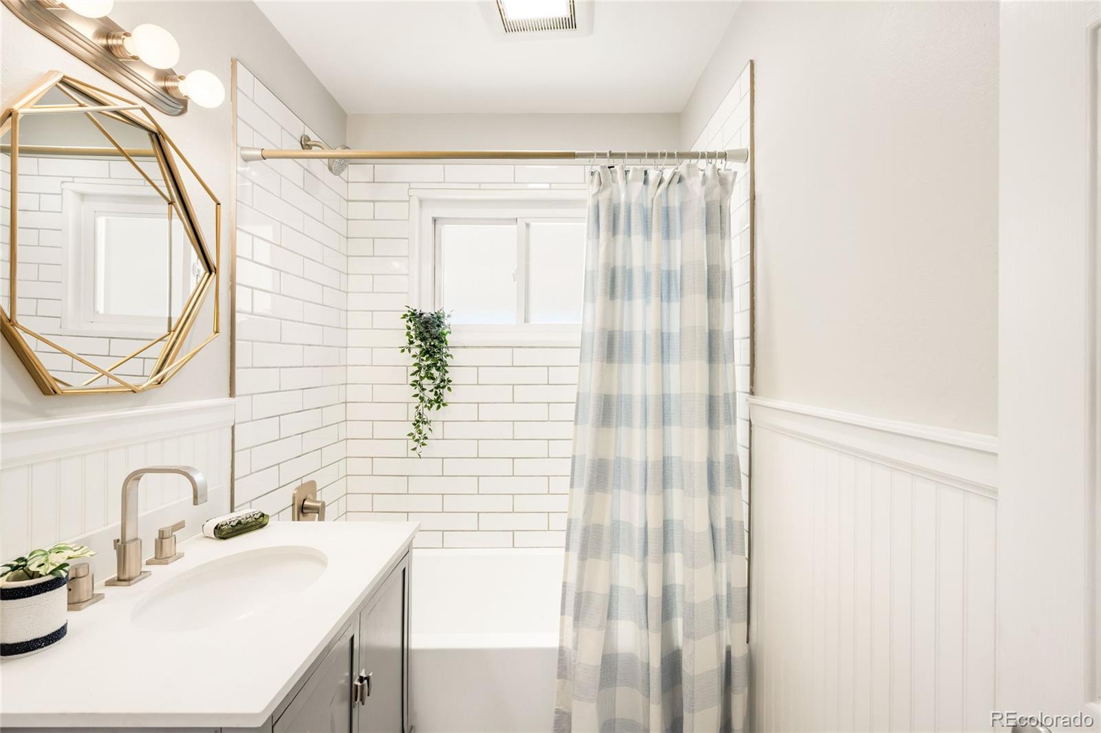 2438 South Perry Street Denver, CO 80219 - Photo 8 of 23 a bathroom with a sink a mirror and a shower
