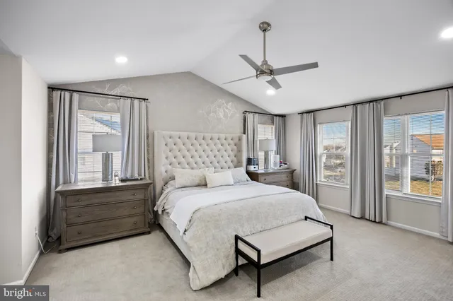 a bedroom with a large bed a chandelier and windows