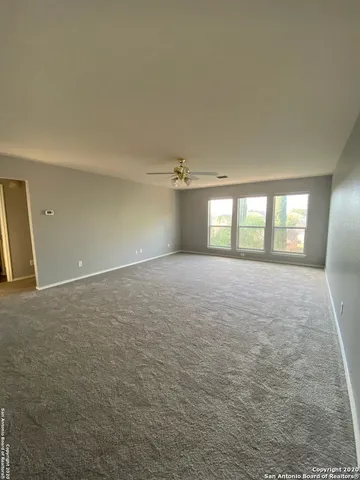 an empty room with windows and ceiling fan