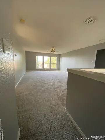 an empty room with windows and fan