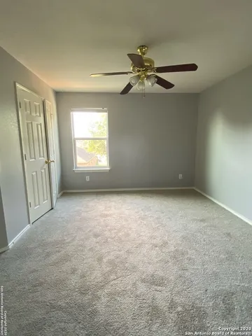 en empty room with windows and ceiling fan