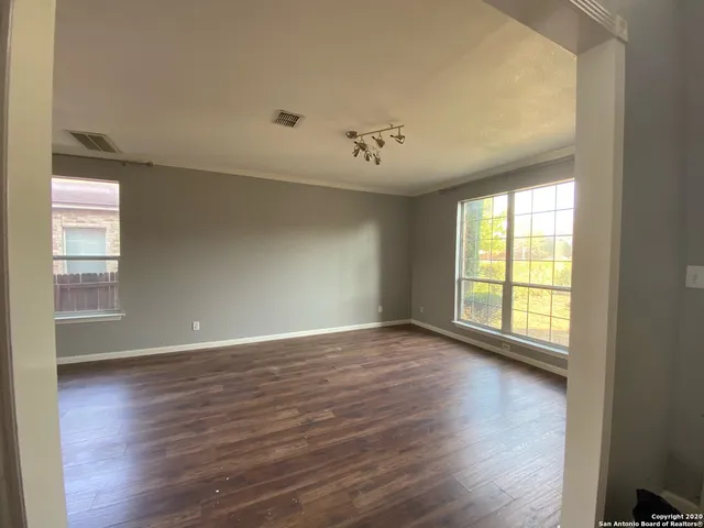 a view of an empty room with wooden floor and a window