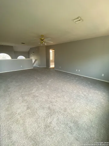 an empty room with a ceiling fan and carpet