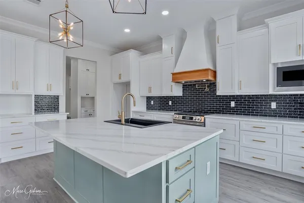 a kitchen with a sink dishwasher a stove and white cabinets with wooden floor