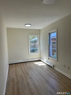 a view of an empty room with a window and wooden floor