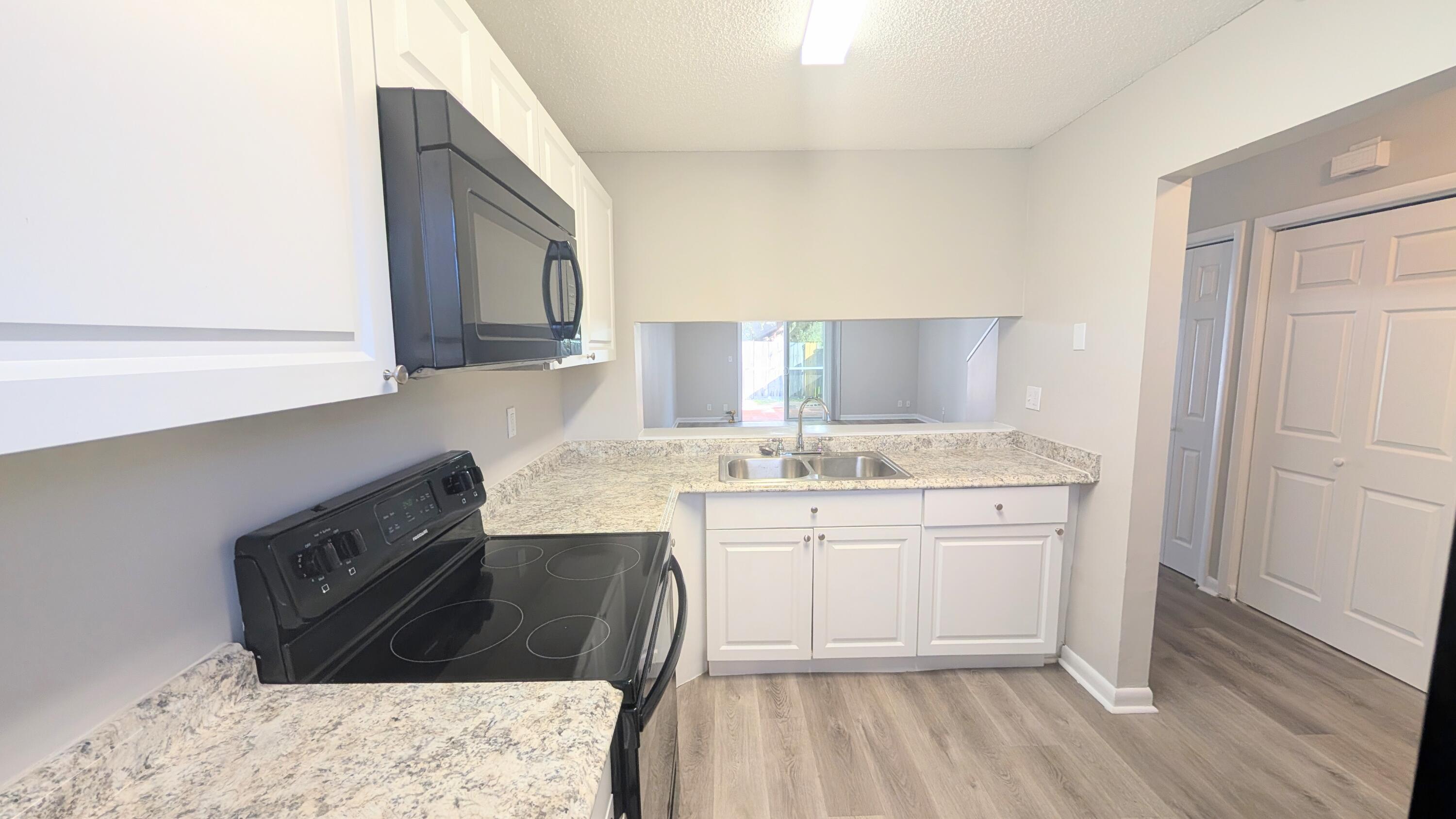 8341 Fairway Road Sunrise, FL 33351 - Photo 3 of 15 a kitchen with granite countertop a sink a stove and cabinets