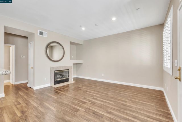 a view of a livingroom with a fireplace a ceiling fan and wooden floor