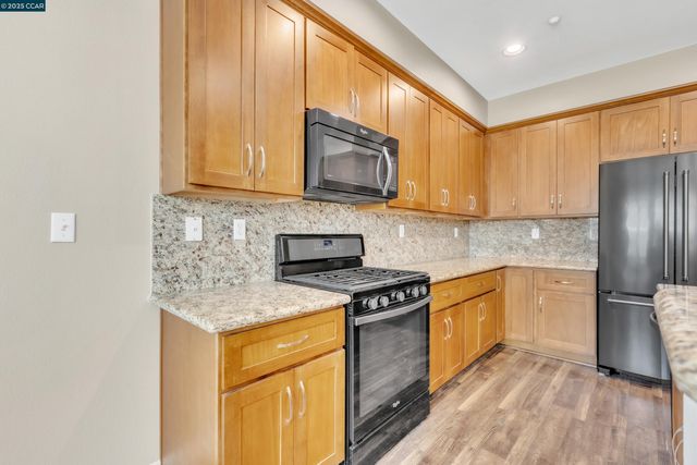 a kitchen with stainless steel appliances granite countertop a stove a sink and a refrigerator