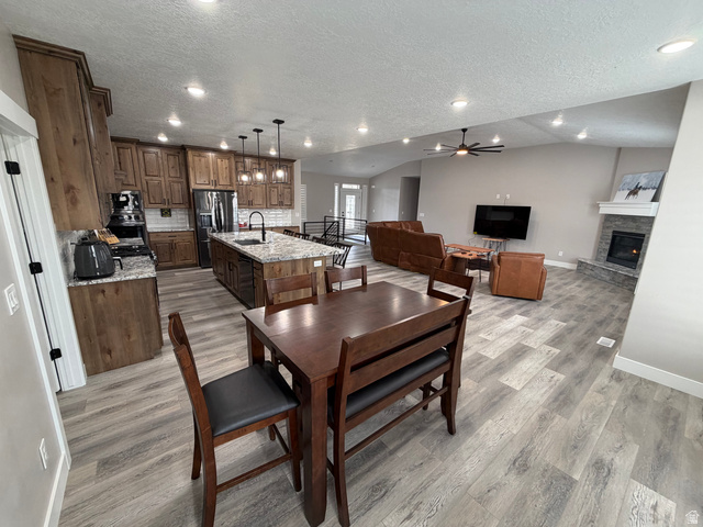 2350 North 1075 West Helper, UT 84526 - Photo 8 of 49 Dining room featuring a textured ceiling, ceiling fan, recessed lighting, light wood-style floors, and a stone fireplace