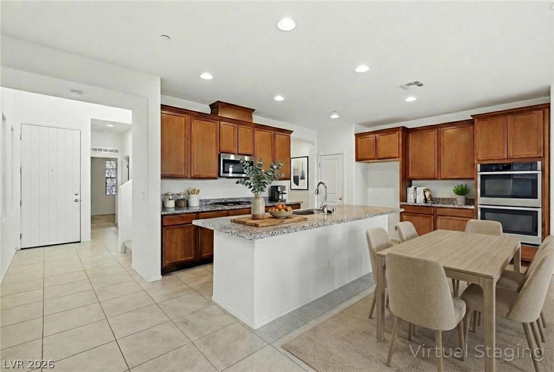 250 Dedication Avenue Henderson, NV 89011 - Photo 17 of 67 Kitchen featuring wood finish cabinetry, stainless steel appliances, light stone countertops, an island with sink, and recessed lighting