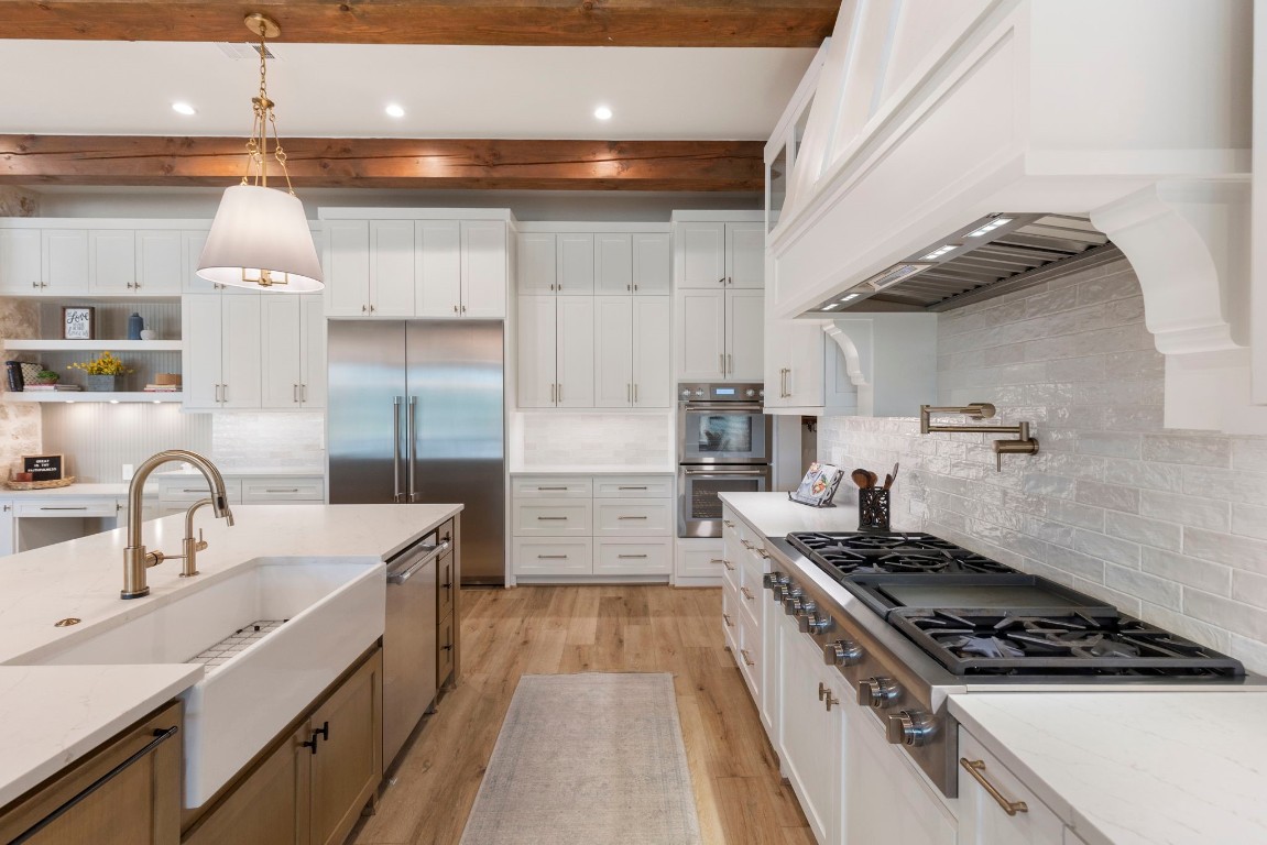 27318 Blue Cedar Lane Spring, TX 77386 - Photo 11 of 45 Chef-inspired kitchen with statement vent hood, quartz island, warm wood beams, and abundant cabinetry.