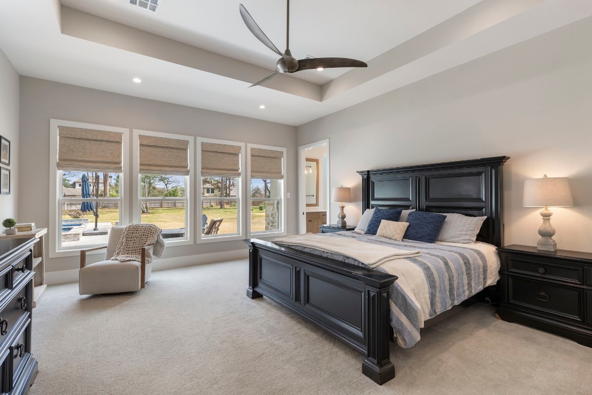 27318 Blue Cedar Lane Spring, TX 77386 - Photo 18 of 45 Primary suite shines with tray ceiling, ceiling fan, and tall windows framing serene backyard views.