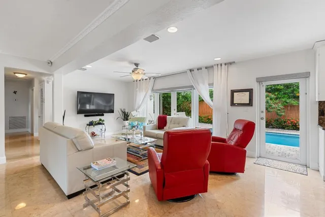 a living room with furniture a flat screen tv and a floor to ceiling window