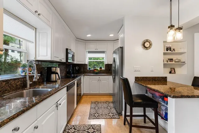 a kitchen with granite countertop a sink stainless steel appliances and cabinets