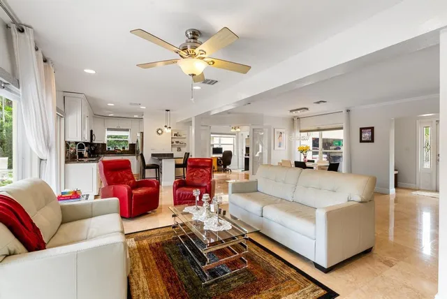 a living room with furniture kitchen view and a chandelier
