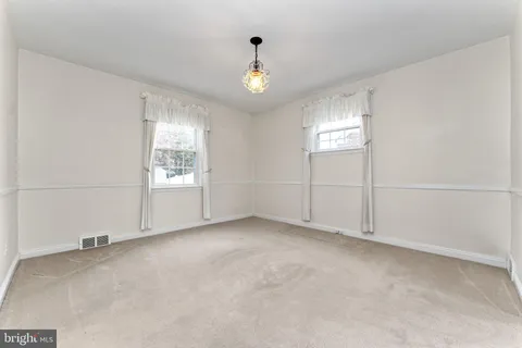 an empty room with windows and chandelier fan