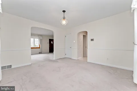 an empty room with chandelier fan and windows