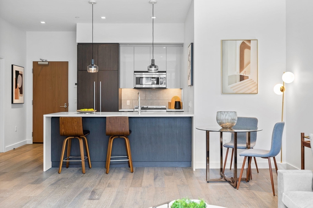 375 Canal Street, Unit PH101 Somerville, MA 02145 - Photo 12 of 39 a kitchen with granite countertop a table chairs refrigerator and microwave