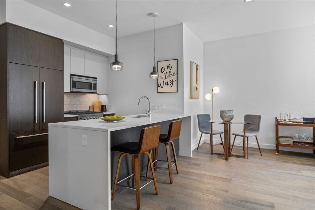 375 Canal Street, Unit PH101 Somerville, MA 02145 - Photo 8 of 39 a kitchen with stainless steel appliances granite countertop a dining table chairs refrigerator and sink