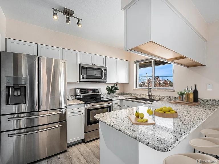 1830 Simms Street Lakewood, CO 80215 - Photo 11 of 31 a kitchen with stainless steel appliances granite countertop a sink a stove and a refrigerator