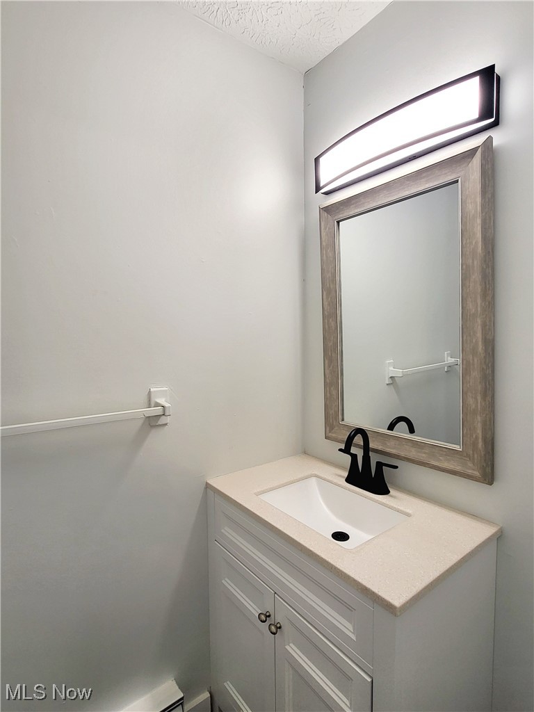 631 Root Road Lorain, OH 44052 - Photo 11 of 24 Bathroom featuring a textured ceiling, vanity, and a baseboard radiator