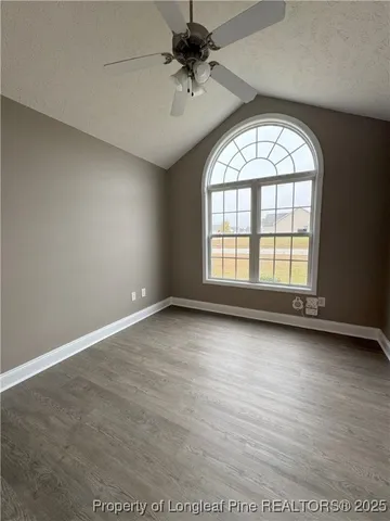 an empty room with windows and ceiling fan