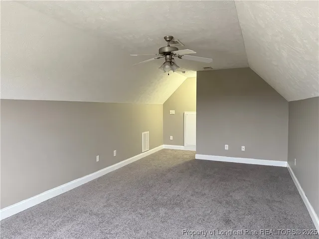 a view of a room with a ceiling fan and carpet