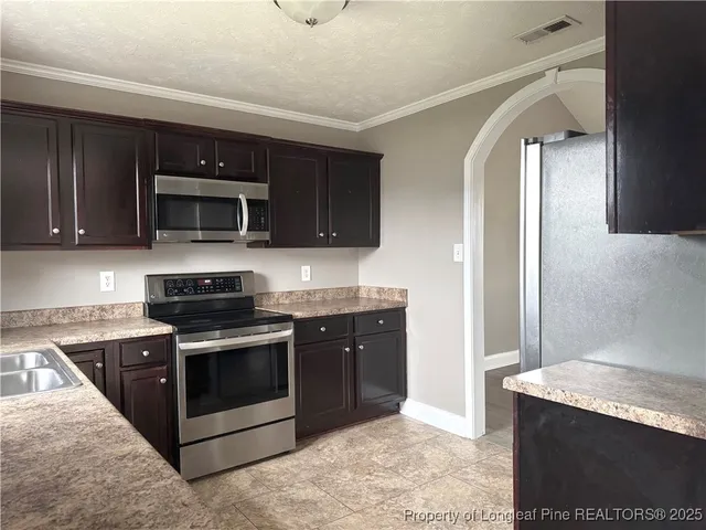 a kitchen with stainless steel appliances granite countertop a stove microwave and sink