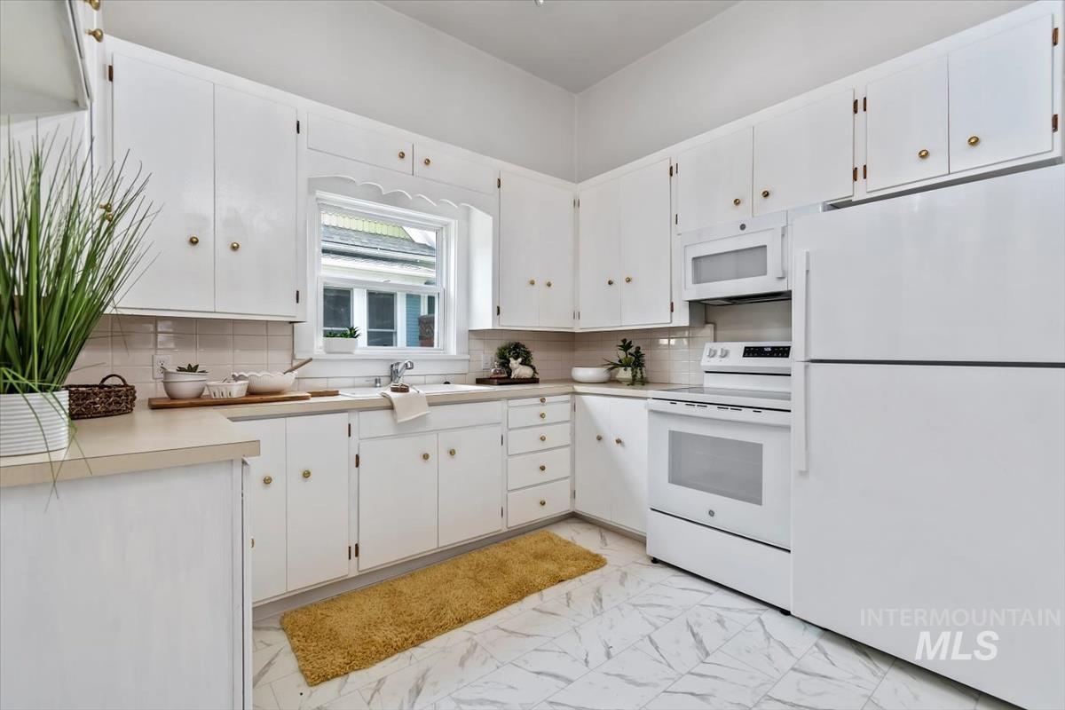 910 North 16th Street Boise, ID 83702 - Photo 18 of 47 Kitchen featuring white cabinetry, light-toned countertops, white tile flooring, and a white appliance suite