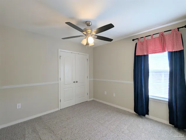 an empty room with closet and a chandelier fan