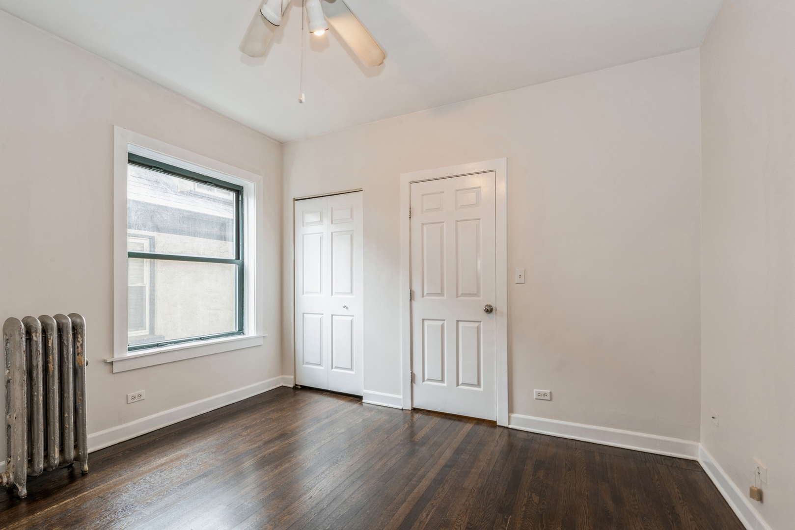 7023 North Sheridan Road, Unit 2E Chicago, IL 60626 - Photo 8 of 10 an empty room with wooden floor cabinet and windows