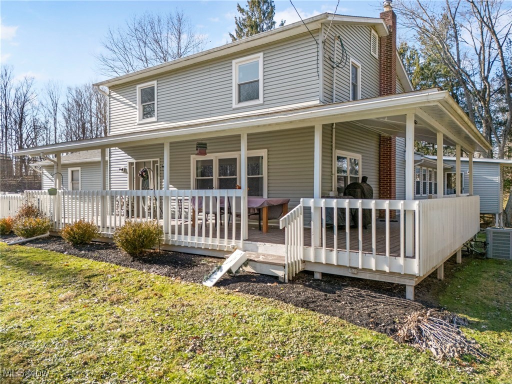 Back of property with a lawn, a chimney, and a porch