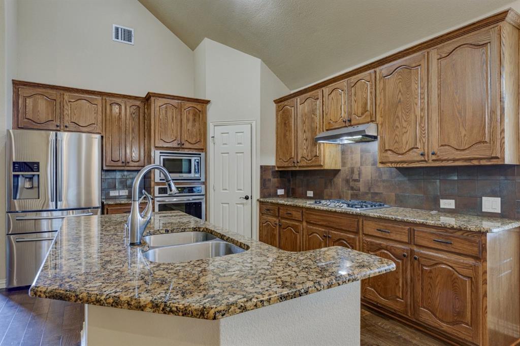 1522 Blue Jay Road Garland, TX 75043 - Photo 13 of 32 Kitchen featuring a double basin stainless steel sink, granite countertops, and wood cabinetry