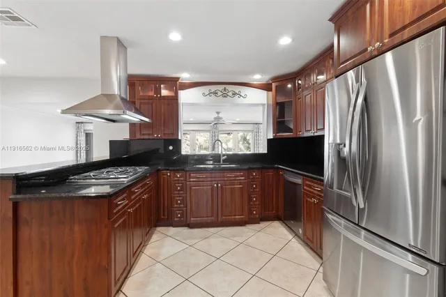 a kitchen with stainless steel appliances granite countertop a refrigerator a stove and a sink