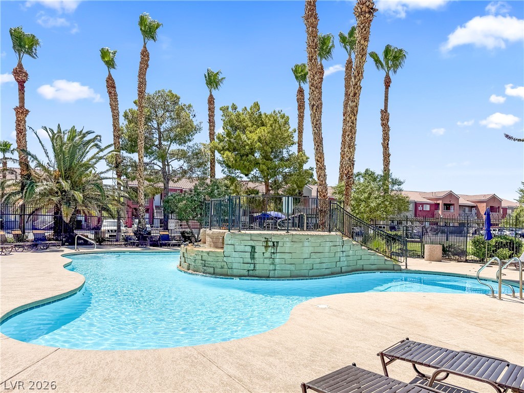 4730 East Craig Road, Unit 1053 Las Vegas, NV 89115 - Photo 25 of 32 A refreshing pool area featuring a unique rock formation and towering palm trees.
