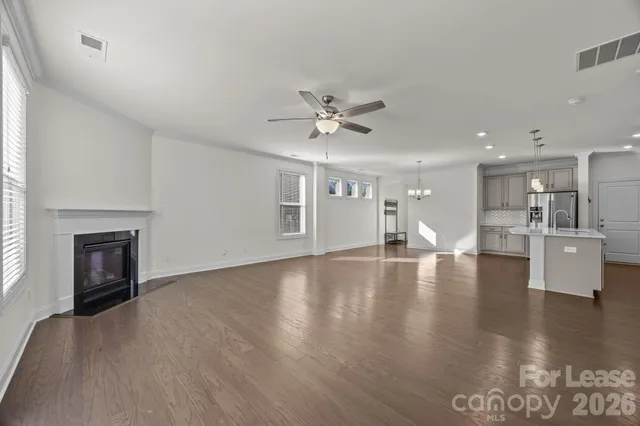 a view of an empty room with kitchen and fireplace
