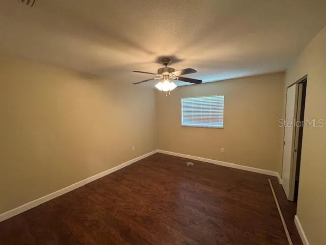 an empty room with a window and a fan