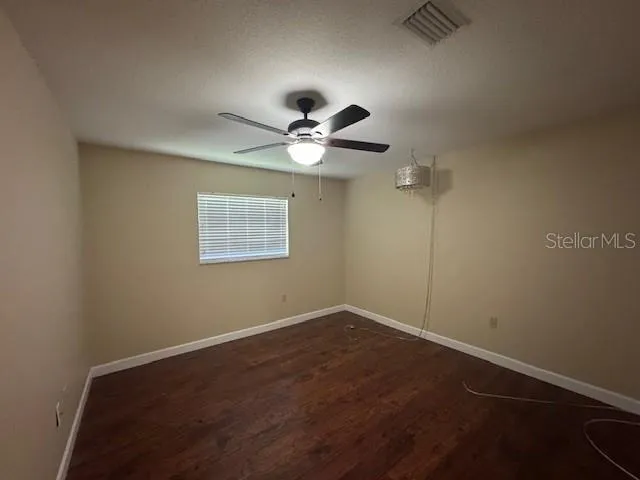 an empty room with a window and a fan