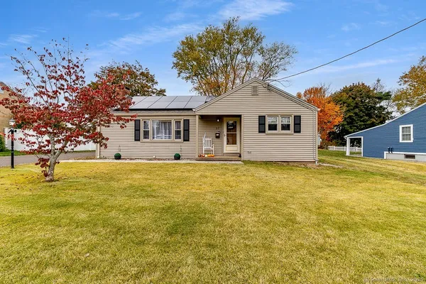 a front view of house with yard and trees in the background