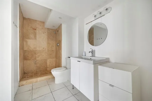 a bathroom with a toilet a sink a mirror and shower