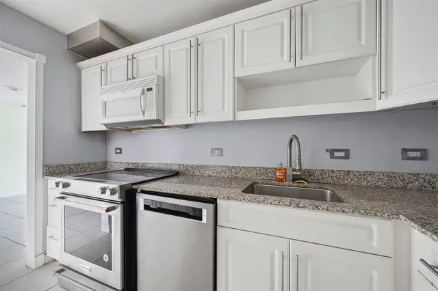 a kitchen with granite countertop white cabinets and a stove